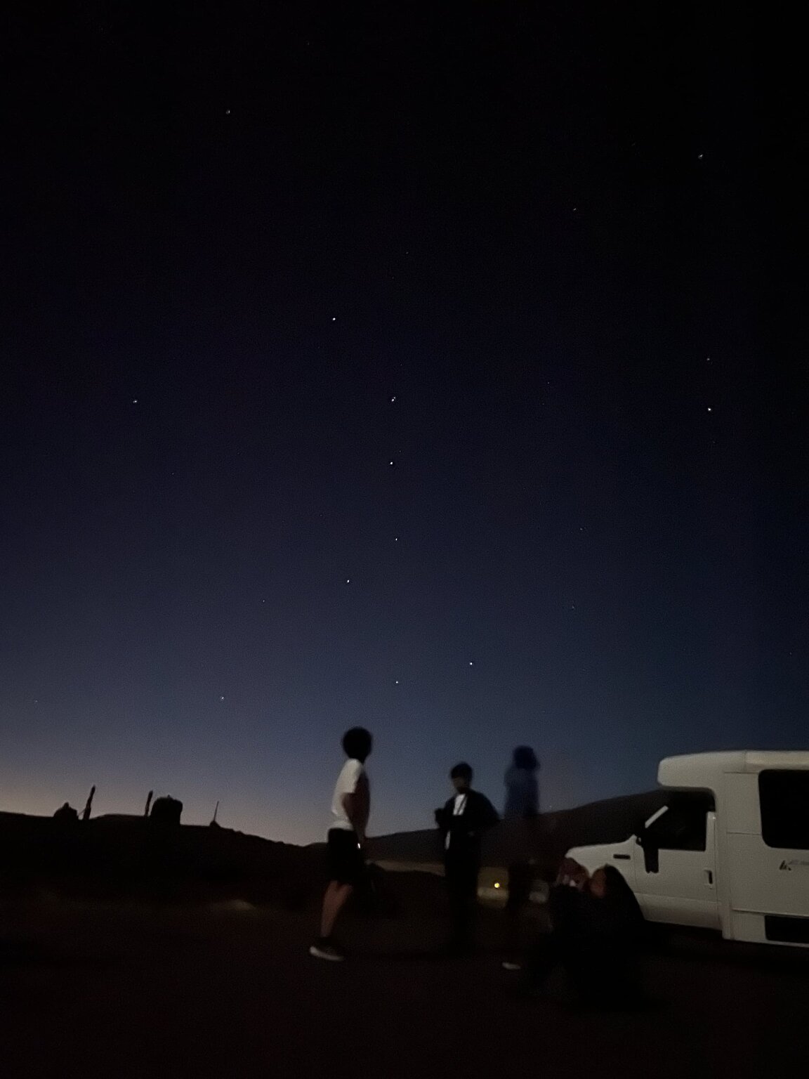 薄明の残る紺色の夜空に星が瞬き、車のそばで生徒たちが空を見上げている